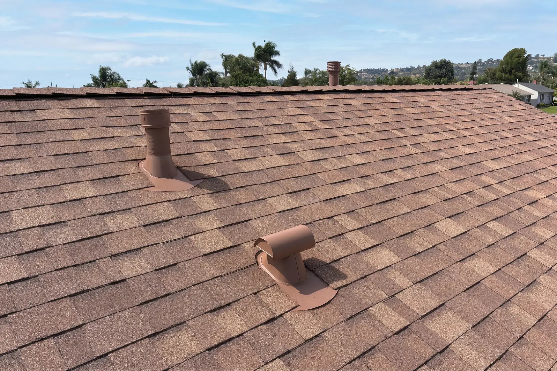 Brown-matched roof vents and pipe boots set in new shingles on the completed roof by Hybrid Renovations, La Habra