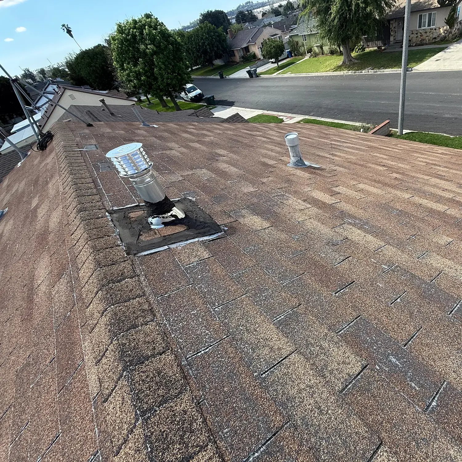 Aged roof with worn shingles and heavily tar-patched vent flashing before the tear-off, La Habra