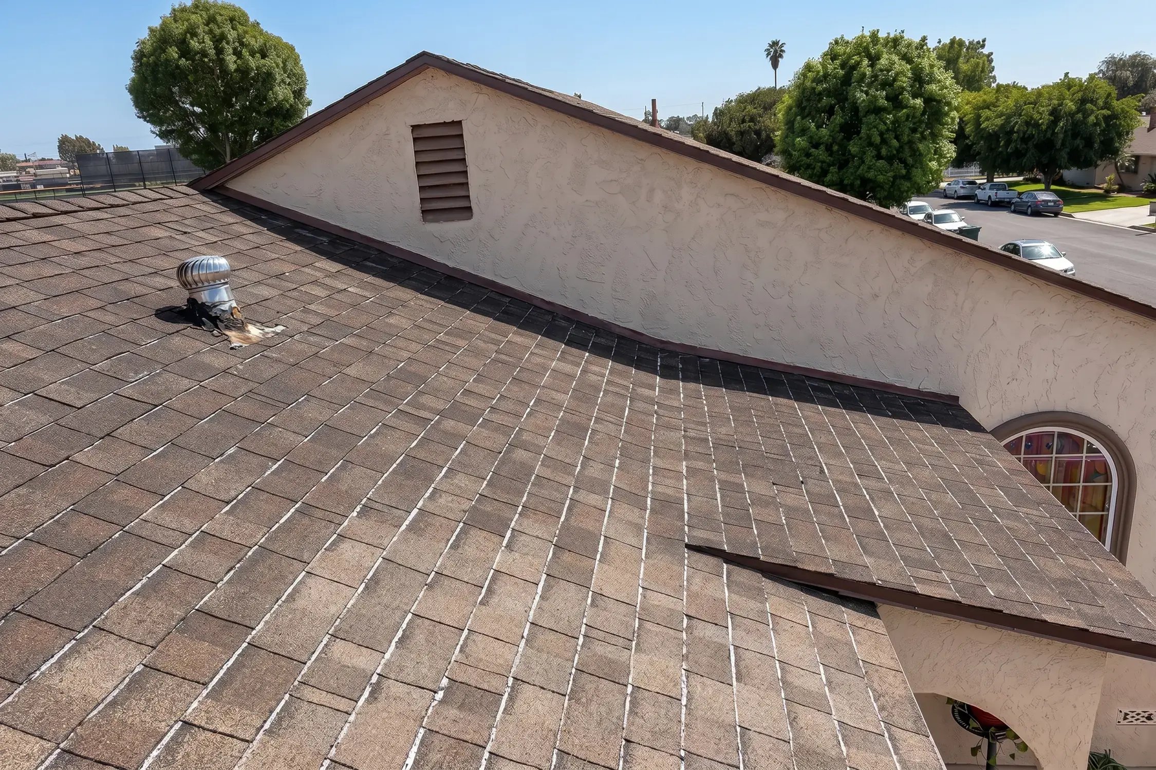 Worn and faded old asphalt shingles with granule loss on the roof before replacement, La Habra