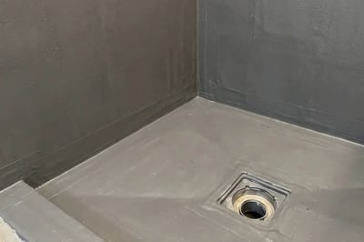 Waterproofing membrane with banded corners bonded to the shower drain flange before tile — Hybrid Renovations
