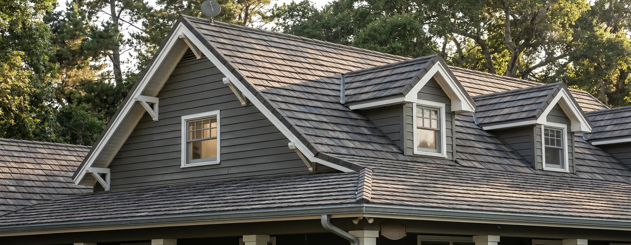 Gray stone-coated steel shake roofing with multiple gabled dormers on a residential home