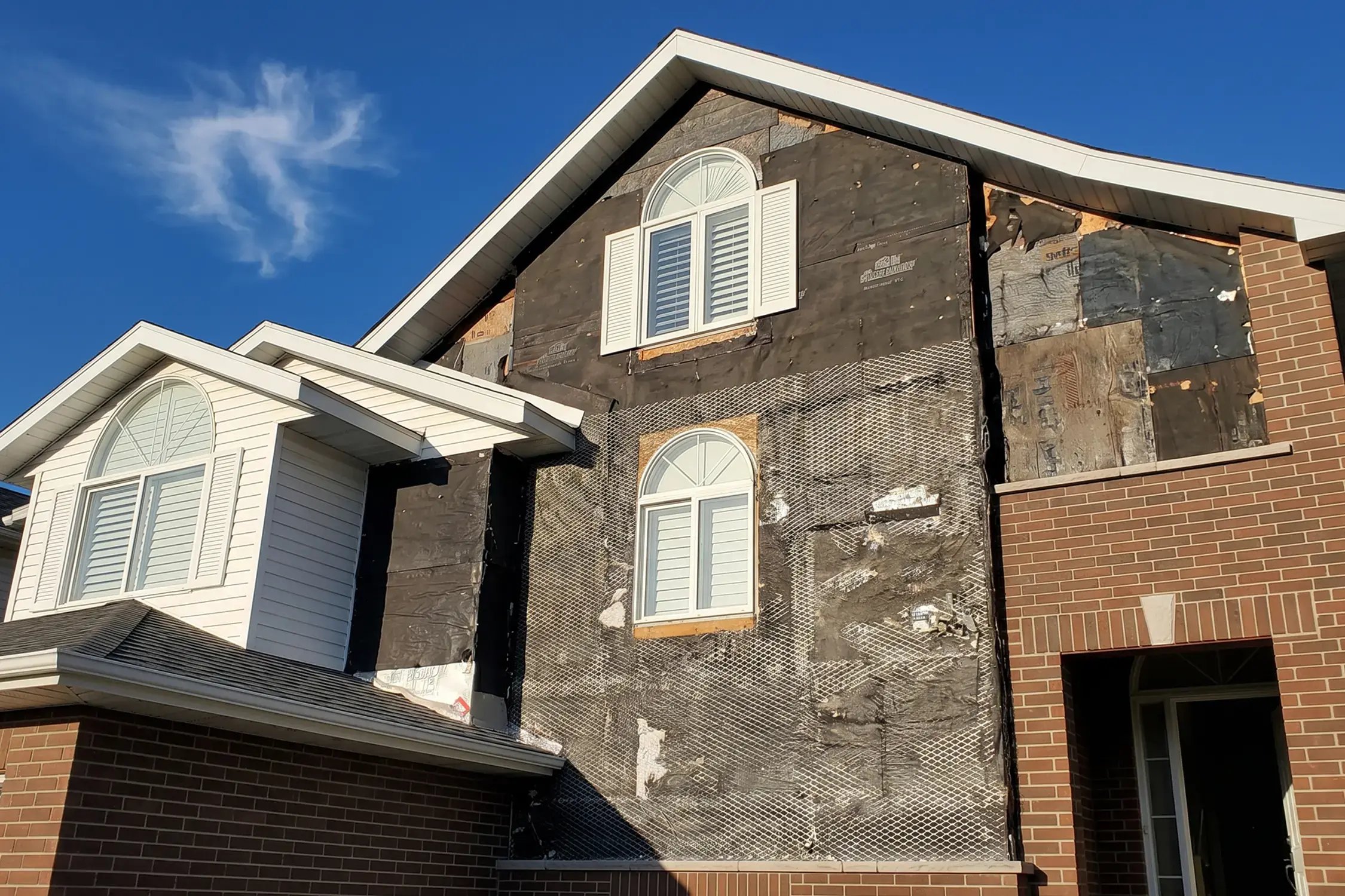 Stucco stripped back to the substrate exposing the wall during water-damage remediation — Hybrid Renovations