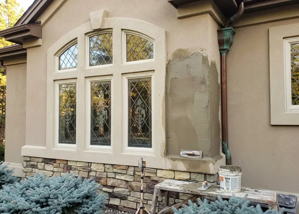 Fresh stucco patch troweled onto an exterior wall during residential stucco repair — Hybrid Renovations