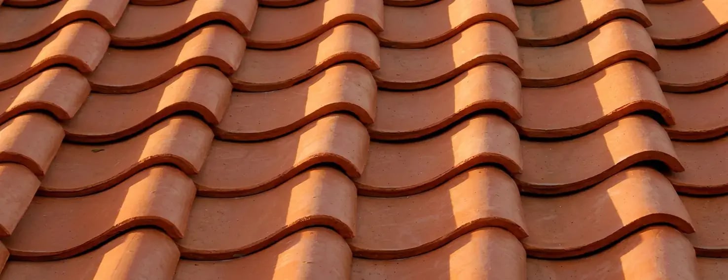 Interlocking clay roof tiles in terracotta, close-up showing the overlapping ribbed courses that lock together