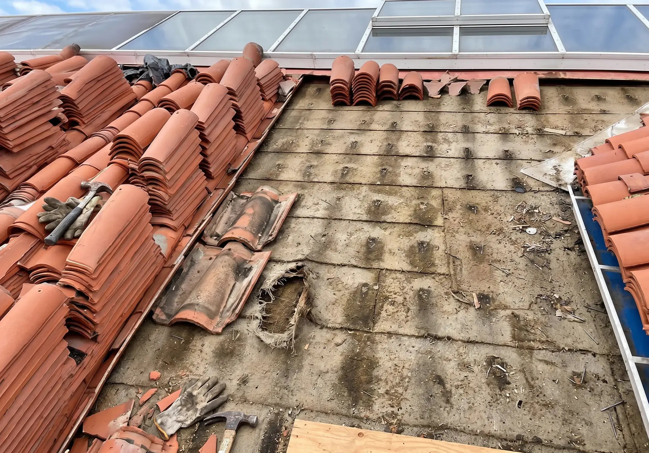 Clay roof tiles lifted and stacked to re-lay new underlayment on a tile roof during roof repair