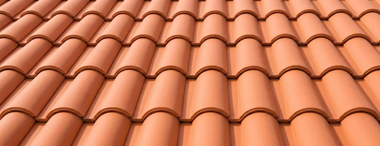 Spanish S-shaped clay roof tiles in bright terracotta, close-up of the uniform wave-profile roofing surface