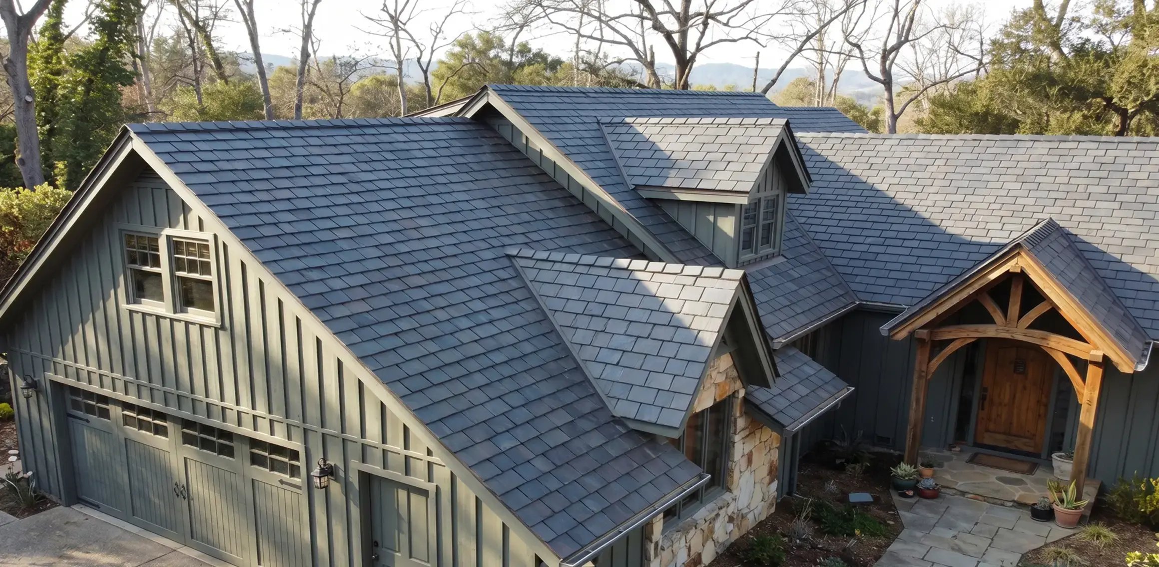 Gray slate roof tiles on a green board-and-batten single-family home with timber entry porch