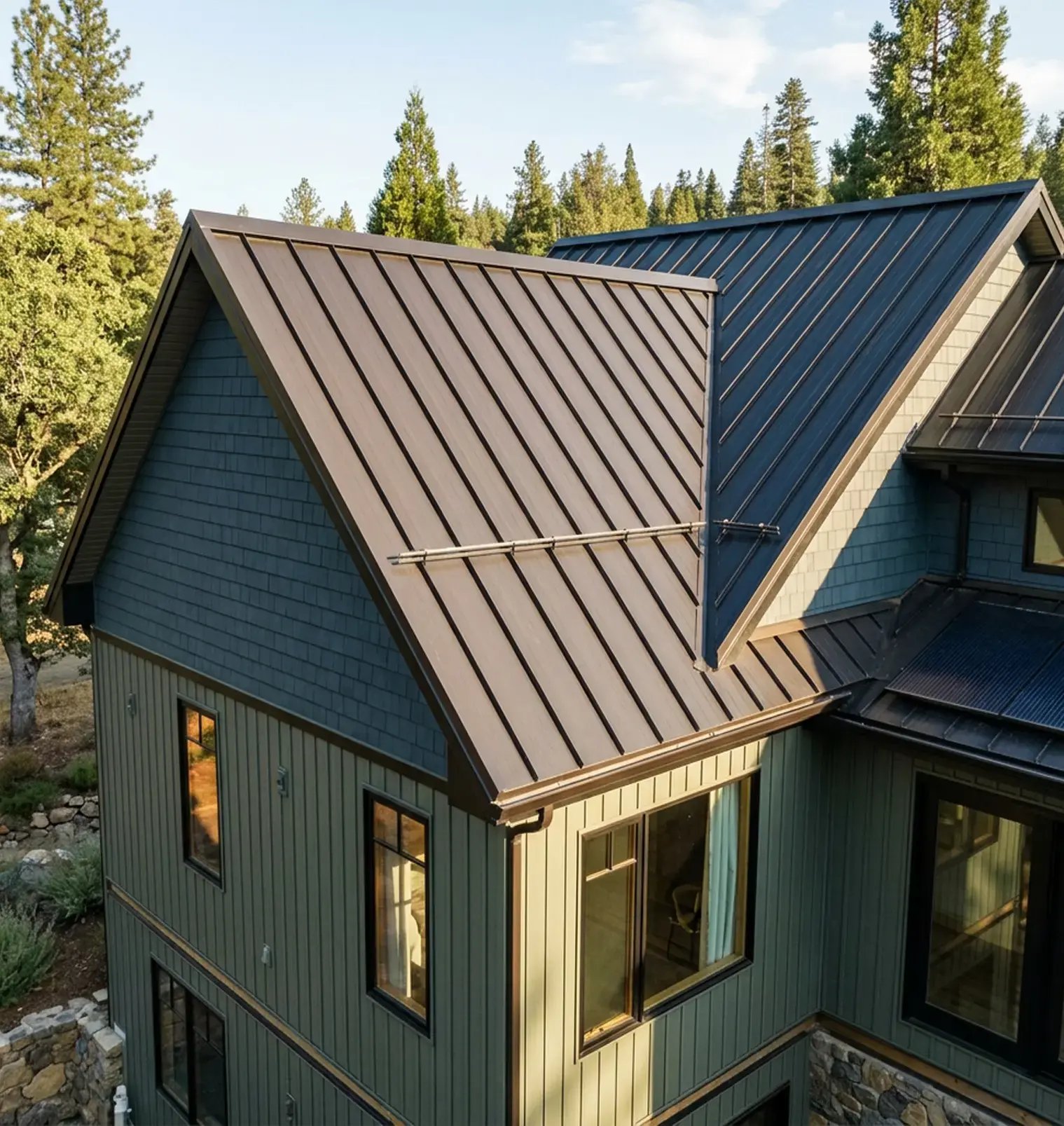 Two-tone bronze and charcoal standing seam metal roof on a home with green board-and-batten siding — Hybrid Renovations